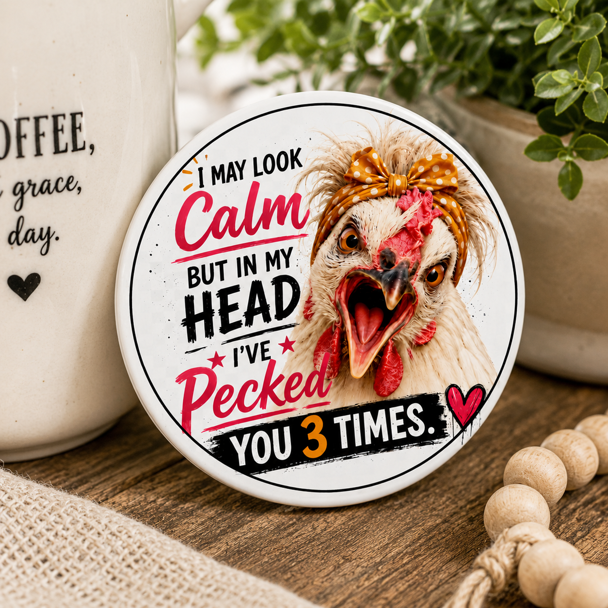 Close-up of the "I May Look Calm" ceramic coaster featuring Lucy & Friends™ artwork with vibrant colors, glossy ceramic finish, and a humorous chicken illustration. Designed by Woodland Willow Designs for farmhouse décor and coffee lovers.