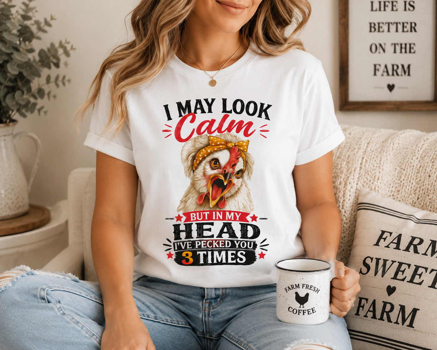 Woman wearing the "I May Look Calm" funny chicken graphic T-shirt by Woodland Willow Designs while relaxing on a cozy farmhouse sofa with a coffee mug. Features the Lucy & Friends™ design with the phrase "I May Look Calm... But In My Head I've Pecked You 3 Times," showcasing the shirt in a warm country-inspired lifestyle setting.