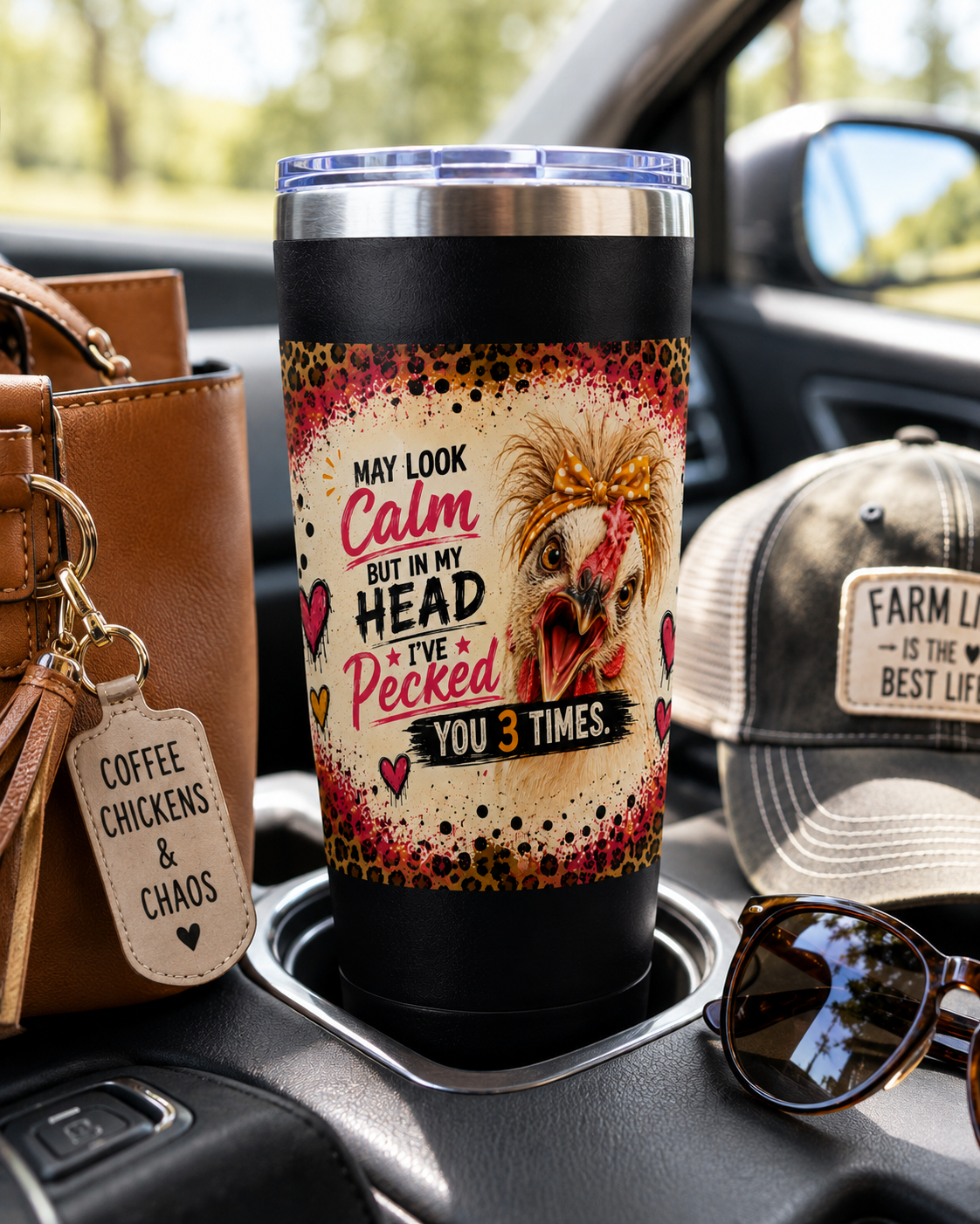 Funny chicken 22oz insulated travel tumbler featuring the "I May Look Calm, But in My Head I've Pecked You 3 Times" design displayed in a vehicle cup holder with a farmhouse hat, sunglasses, and everyday travel accessories.