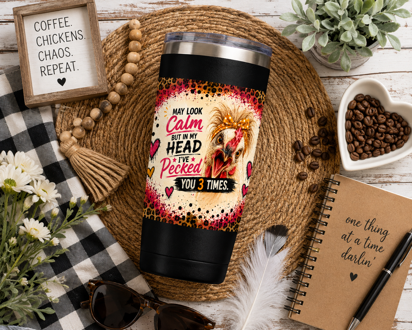 Top-down flat lay of a funny chicken 22oz insulated travel tumbler featuring the "I May Look Calm, But in My Head I've Pecked You 3 Times" design surrounded by farmhouse décor, coffee beans, flowers, a notebook, and rustic country accessories.